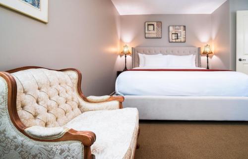 een slaapkamer met een wit bed en een stoel bij Sunrise Valley Suite in West Kelowna
