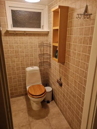 a bathroom with a toilet with a wooden toilet seat at Trevligt källare lägenhet in Jönköping