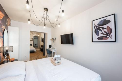 a bedroom with a white bed and a chandelier at Penzion Mácha in Litoměřice