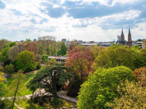 uma vista para um parque com árvores e edifícios em Mercure Antwerp City Centre em Antuérpia