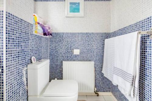 a bathroom with a white toilet and blue tiles at Buzz Crib in London