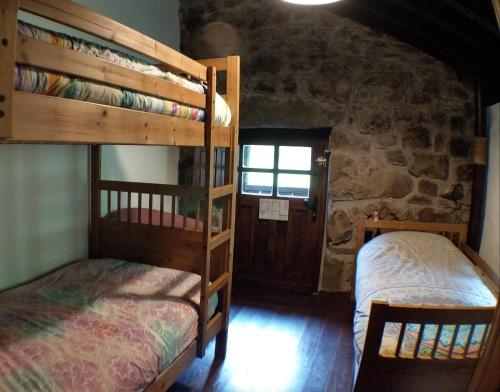two bunk beds in a room with a stone wall at Pidream Cottage . Cabañas de Pisueña in Selaya