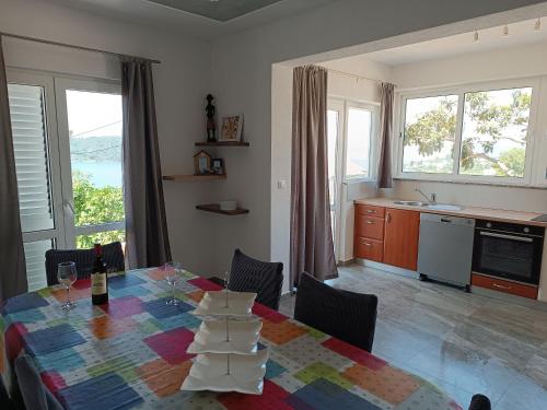 a dining room with a table and a kitchen with windows at Apartments Solta in Nečujam