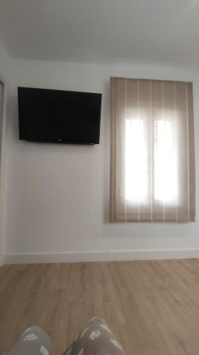 a living room with a flat screen tv and a window at Casa con encanto in Corbera de Llobregat