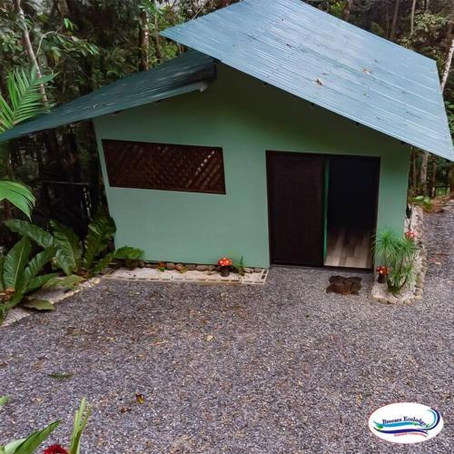 un petit bâtiment vert avec un toit bleu dans l'établissement Breezes Ecolodge, à San Ramón