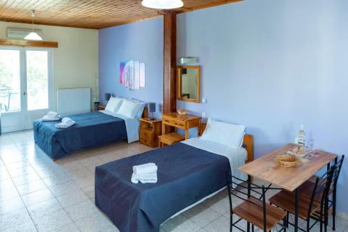 ein Hotelzimmer mit 2 Betten, einem Tisch und einem sidx sidx in der Unterkunft Zois Apartments in Nikiana