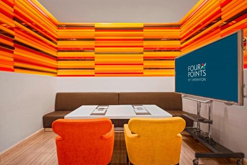 a meeting room with a table and two orange chairs at Four Points by Sheraton Bangkok, Sukhumvit 15 in Bangkok