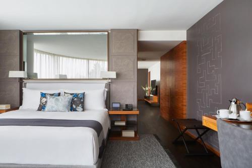 a bedroom with a large white bed and a mirror at Las Alcobas, a Luxury Collection Hotel, Mexico City in Mexico City