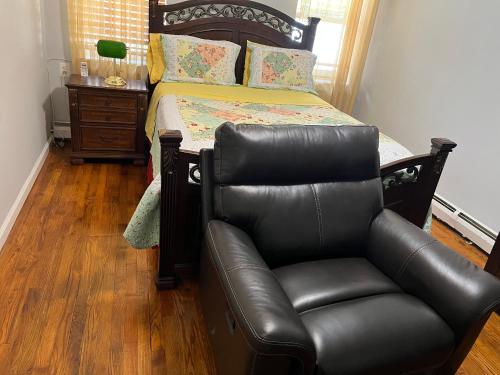 a bedroom with a bed and a leather chair at Cozy Place To Stay in Brooklyn in Brooklyn