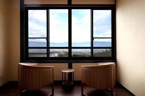 a room with two chairs and a large window at Yakushidaira Akanejyuku in Matsumoto