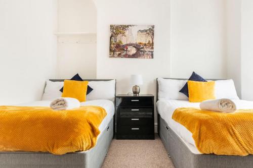 1 dormitorio con 2 camas con mantas amarillas y una foto en Home Near Anfield and Everton FC with FREE Parking, en Liverpool