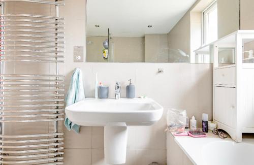a white bathroom with a sink and a mirror at Central London Comfortable Homestyle Apartment in London