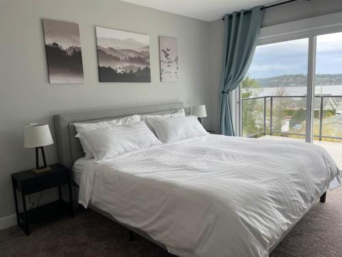 a bedroom with a white bed and a large window at Ocean View Oasis in Campbell River