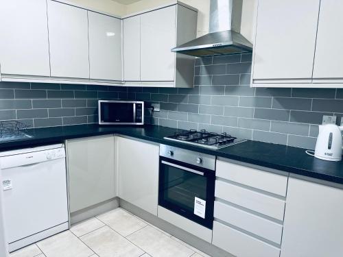 a kitchen with white cabinets and a stove top oven at Glory House in Ilford