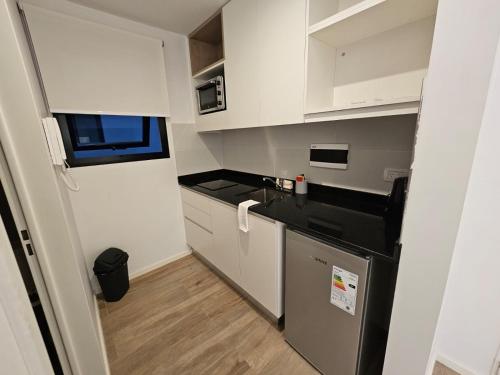 una pequeña cocina con armarios blancos y electrodomésticos negros en Sancer House Bs As en Buenos Aires