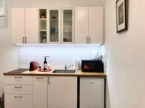 a kitchen with white cabinets and a sink and a microwave at Nick's place-brandnew, central and quiet apt by Margit bridge in Budapest