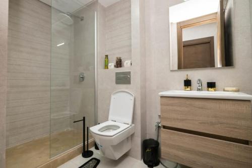 La salle de bains est pourvue de toilettes et d'une douche en verre. dans l'établissement Appartement spacieux avec piscine à Dar Bouazza - Casablanca, à Casablanca