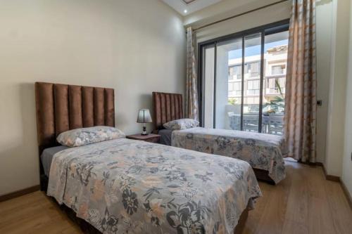 1 dormitorio con 2 camas y ventana en Appartement spacieux avec piscine à Dar Bouazza - Casablanca, en Casablanca