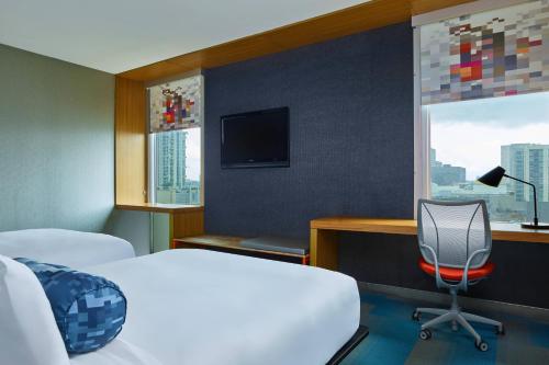 1 dormitorio con 1 cama, escritorio y TV en Aloft Houston by the Galleria en Houston