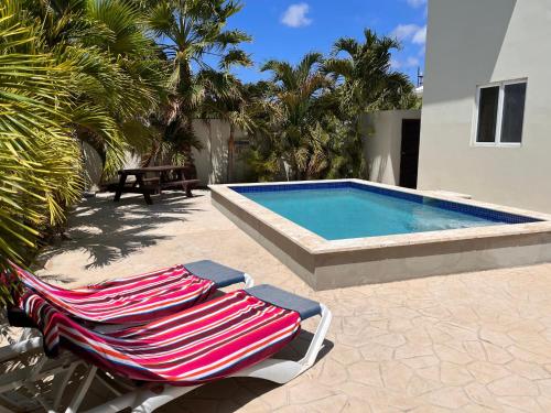 a pair of lounge chairs next to a swimming pool at Andira Apartments in Willemstad