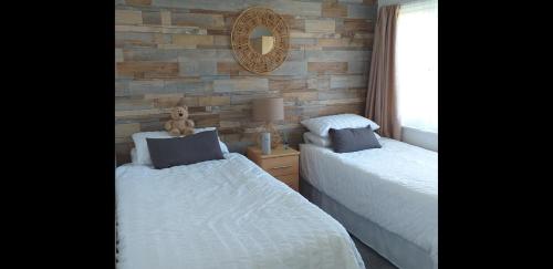 a bedroom with two beds and a mirror on the wall at Seadell 2 Bed Coastal Chalet in Hemsby Great Yar in Hemsby