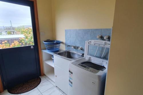 a kitchen with a sink and a washing machine at A Hidden Tranquil Gem on Douglas in Bicheno