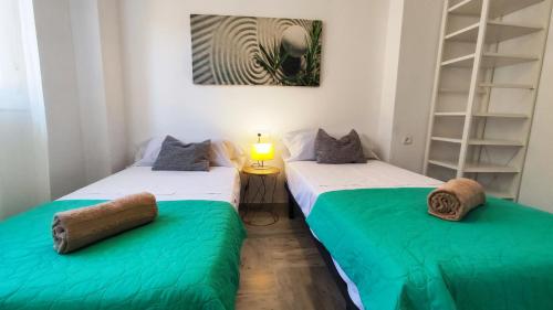 - 2 lits dans une chambre avec des draps verts et blancs dans l'établissement 2BDR Penthouse, terrace, BBQ, pools and sea view in Benalmádena, à Benalmádena