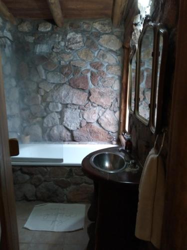 baño con lavabo y pared de piedra en Rincón Alto Cabañas en Nono