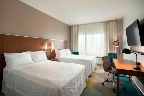 um quarto de hotel com duas camas e uma secretária em Four Points by Sheraton Miami Airport em Miami