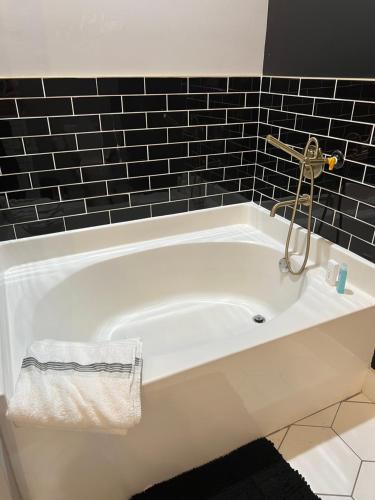 a white bath tub in a bathroom with black tiles at Welcome to the AUC Modern Unit in Atlanta