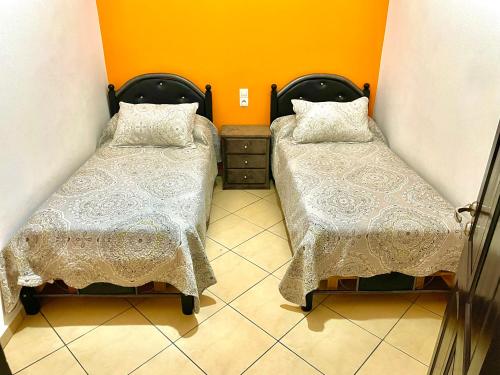 two beds in a small room with orange walls at Dar Rachid in Asilah