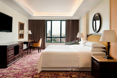Habitación de hotel con cama grande y escritorio. en Sheraton Hanoi Hotel, en Hanói