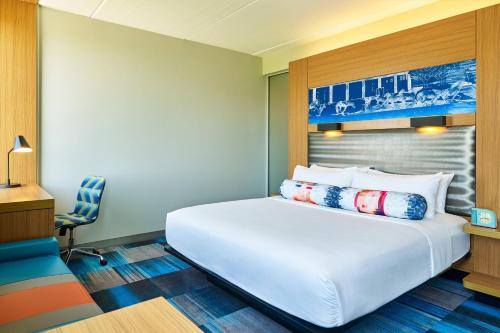 a bedroom with a large white bed and a chair at Aloft Hotel Las Colinas in Irving