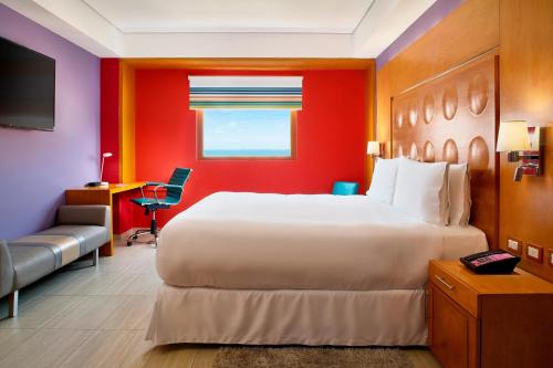 una habitación de hotel con una cama grande y una silla en Aloft Cancun en Cancún