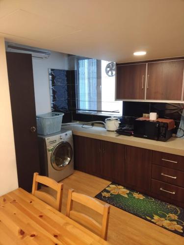 a kitchen with a washing machine and a table with chairs at Grand Illusyin in Shah Alam