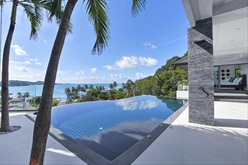 an infinity pool in the backyard of a house with palm trees at Luxury Villa in Cape Panwa in Panwa Beach