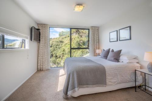 a white bedroom with a bed and a large window at Million Dollar View - Takamatua Holiday Home in Akaroa