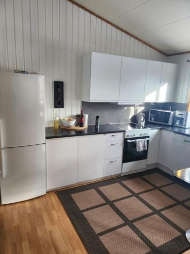 una cocina con electrodomésticos blancos y armarios blancos en Apartment By The Lakeside, en Tromsø