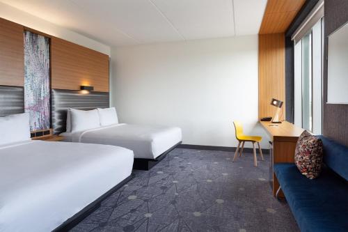 a hotel room with two beds and a desk at Aloft Jacksonville Tapestry Park in Jacksonville