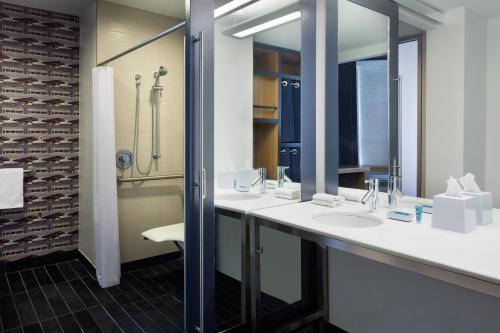 a bathroom with two sinks and a shower at Aloft Jacksonville Tapestry Park in Jacksonville