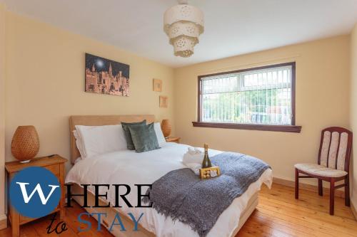 a bedroom with a bed and a chair and a window at Lovely apartment by the Hillwood Park-Free Parking in Edinburgh