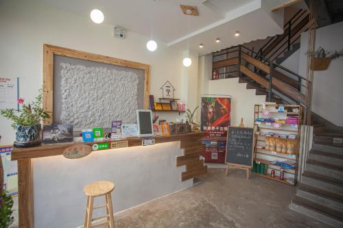 a restaurant with a counter with a stool and stairs at Zhangjiajie One Art Guesthouse in Zhangjiajie