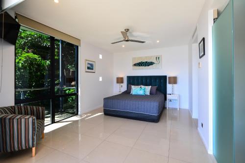 a bedroom with a bed and a large window at Edge Waterfront Apartments in Hamilton Island