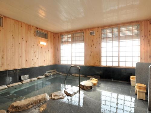 a bathroom with a tub with rocks in it at Ryokan Okayama in Akakura
