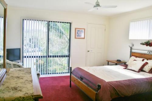 a bedroom with a bed and a large window at 526 Arthur Kaine Dr Merimbula in Merimbula