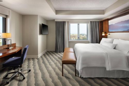 a hotel room with a large bed and a desk at The Westin Pasadena in Pasadena