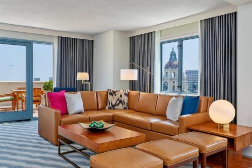 a living room with a brown couch and large windows at The Westin Pasadena in Pasadena