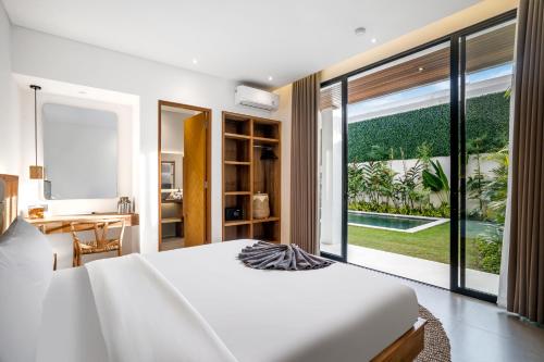 - une chambre avec un grand lit blanc et une grande fenêtre dans l'établissement Villa Bhima by BaliSuperHost, à Canggu