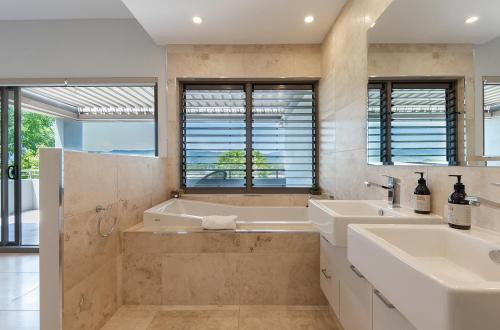 a bathroom with two sinks and a tub and a shower at Villa On The Hill - Spacious Tropical Panorama in Port Douglas