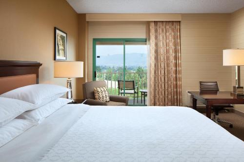 ミルピータスにあるSheraton San Joseのベッドと机と窓があるホテルの部屋